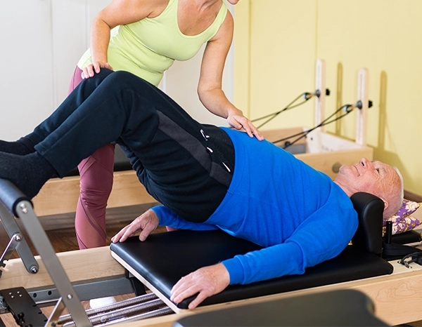 older man in a pilates session on reformer